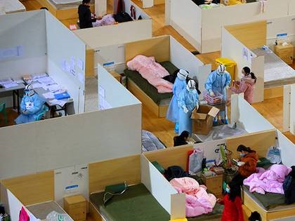 Personal médico vestido con trajes protectores distribuye comida en un estadio deportivo que se ha convertido en un hospital improvisado para tratar a los pacientes del nuevo coronavirus, en Wuhan, el 2 de marzo de 2020 (China Daily vía Reuters)